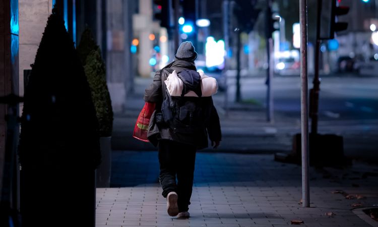 Woman walking along street with bedding roll.