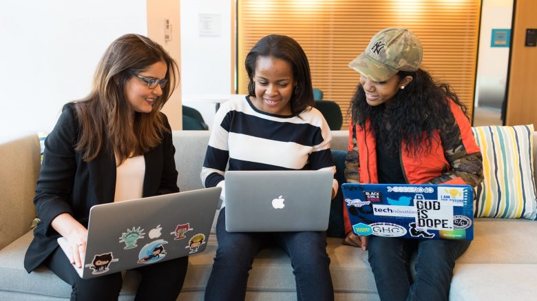 Three young women talking with laptops