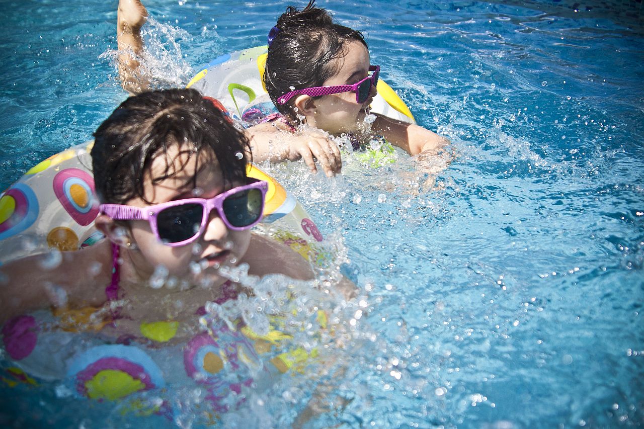 Girls swimming in pool with sunglasses and rubber rings